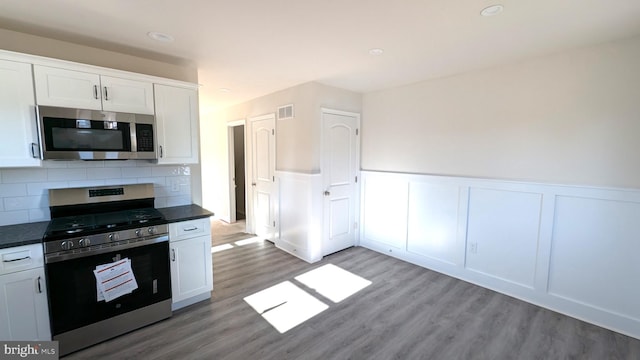 kitchen with white cabinets, stainless steel appliances, tasteful backsplash, and hardwood / wood-style flooring