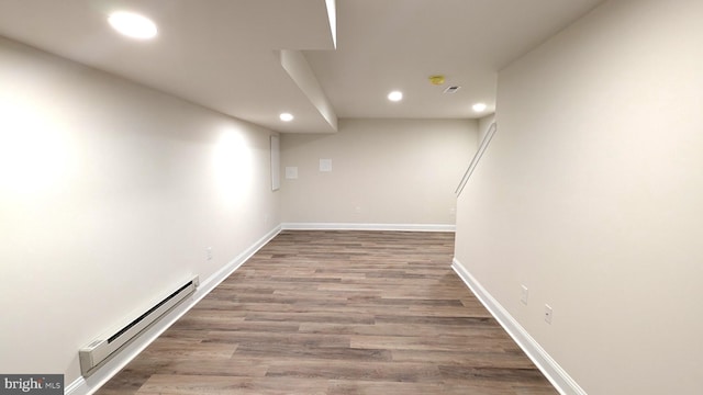 basement with wood-type flooring and a baseboard heating unit