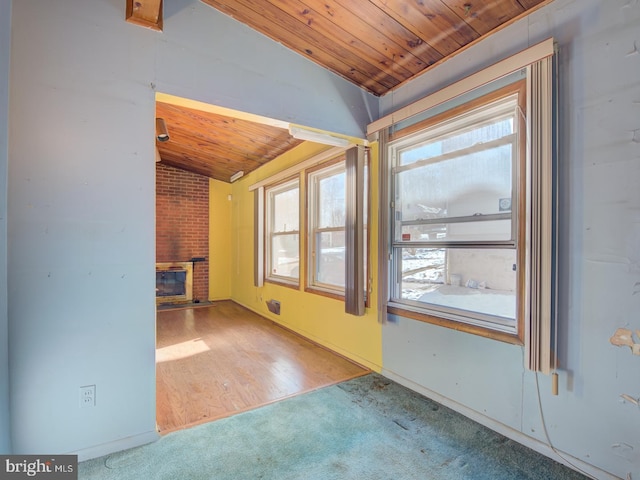 unfurnished room featuring carpet, wooden ceiling, vaulted ceiling, and a brick fireplace