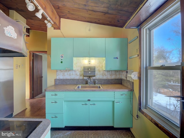 kitchen with tasteful backsplash, wood ceiling, rail lighting, sink, and lofted ceiling