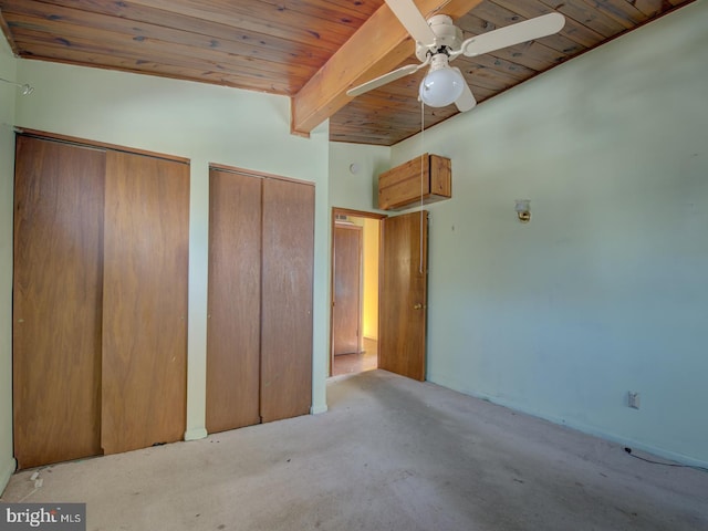 unfurnished bedroom featuring ceiling fan, lofted ceiling with beams, wooden ceiling, and two closets