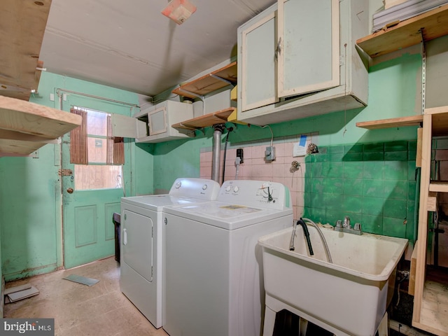 clothes washing area featuring sink, cabinets, and separate washer and dryer