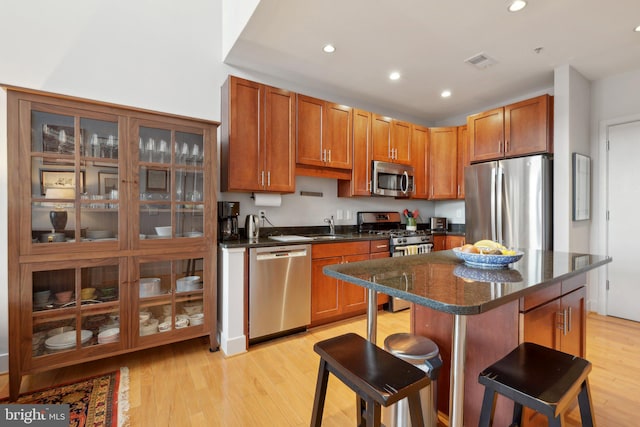 kitchen featuring a kitchen bar, appliances with stainless steel finishes, sink, light hardwood / wood-style flooring, and a kitchen island