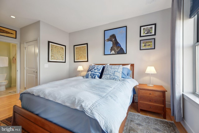 bedroom with connected bathroom and hardwood / wood-style floors