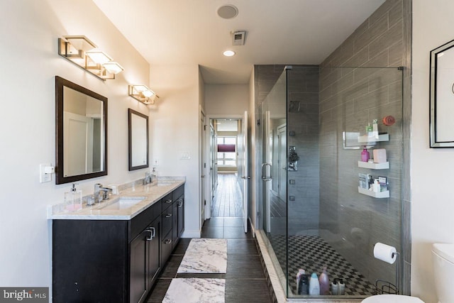 bathroom with tile patterned floors, vanity, a shower with shower door, and toilet