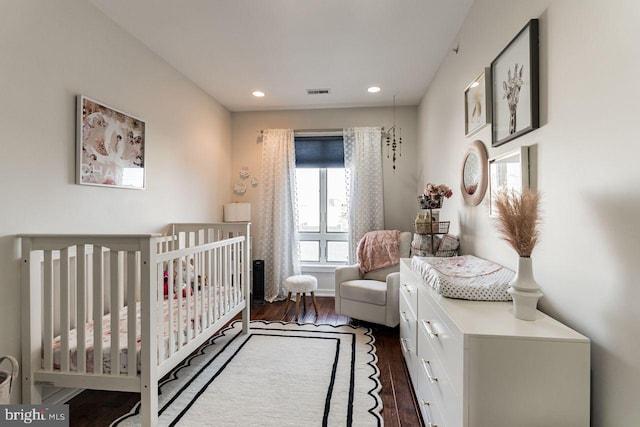 bedroom featuring dark hardwood / wood-style floors and a nursery area