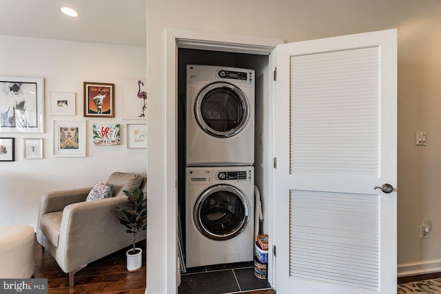 laundry area with stacked washer and dryer and dark tile patterned flooring