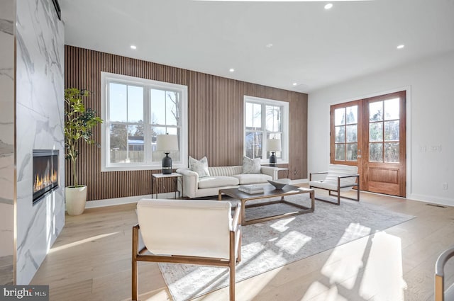 living room with french doors, a premium fireplace, and light wood-type flooring