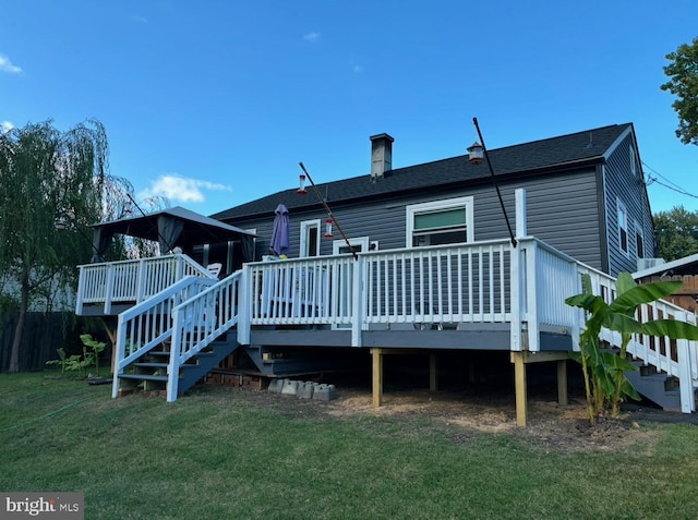 back of property with a wooden deck, a gazebo, and a yard