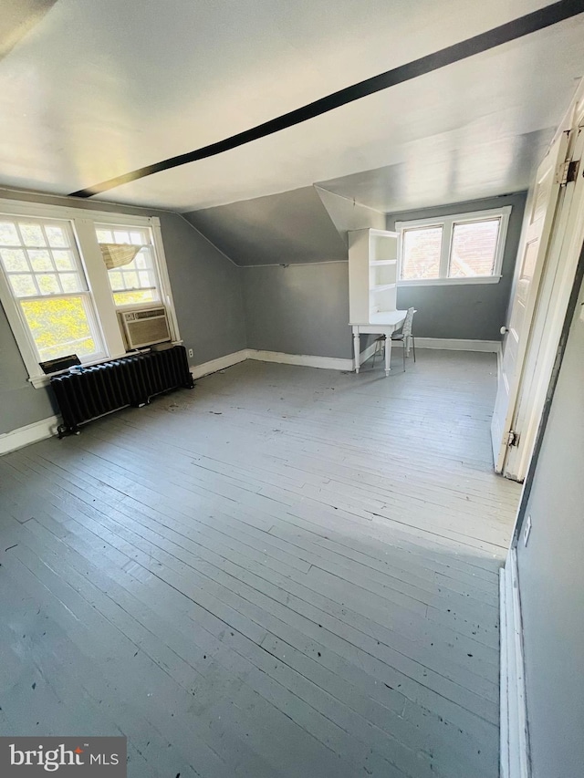 additional living space with cooling unit, vaulted ceiling, and light wood-type flooring