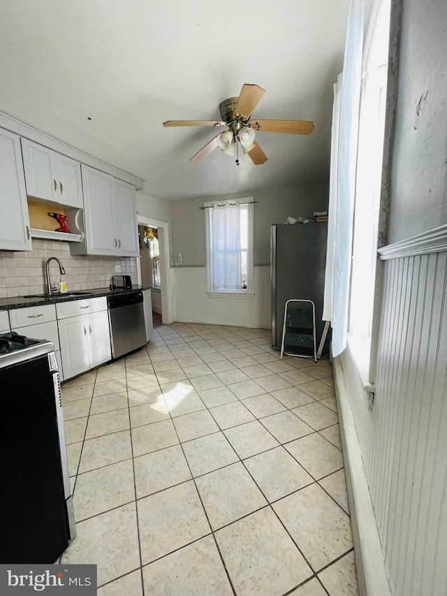 kitchen with sink, white cabinetry, backsplash, stainless steel appliances, and light tile patterned flooring