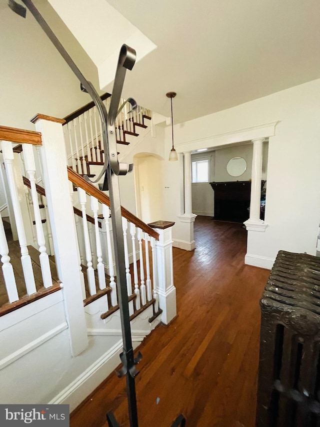 stairway featuring hardwood / wood-style flooring and ornate columns