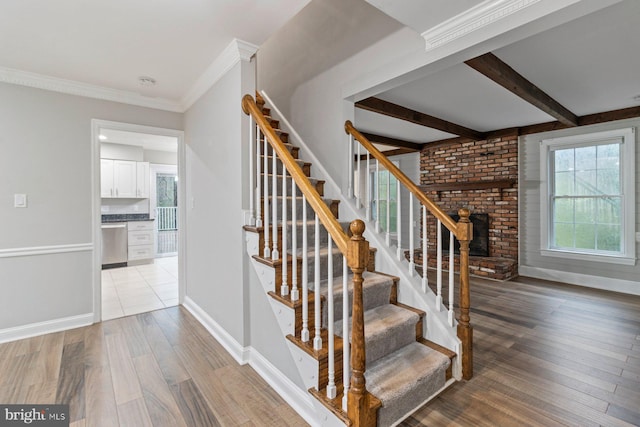 stairs with wood-type flooring, ornamental molding, and beamed ceiling