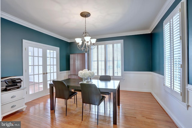 dining room featuring french doors, an inviting chandelier, ornamental molding, and light hardwood / wood-style flooring