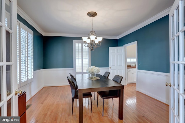 dining space featuring light wood-type flooring, plenty of natural light, crown molding, and a chandelier