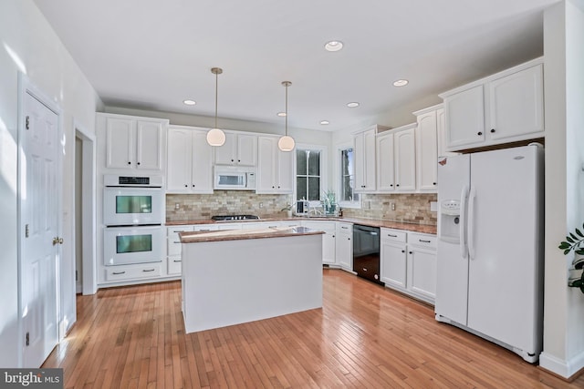 kitchen with decorative light fixtures, a kitchen island, black appliances, and white cabinetry