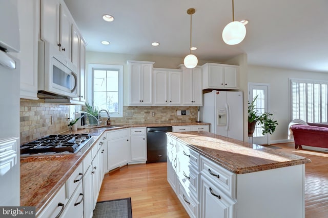 kitchen featuring white appliances, white cabinets, a kitchen island, and sink