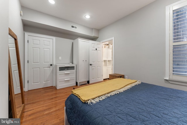 bedroom with ensuite bathroom and light hardwood / wood-style flooring