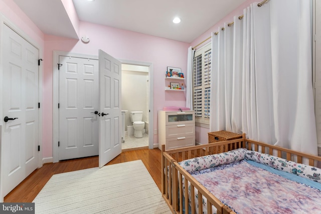 bedroom with light hardwood / wood-style floors and a nursery area