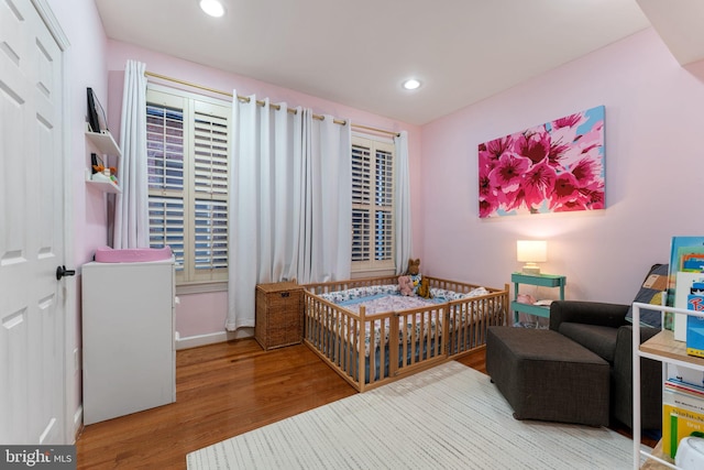 bedroom with wood-type flooring and a crib