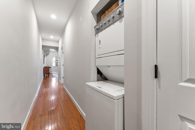 corridor with stacked washer / dryer and hardwood / wood-style floors