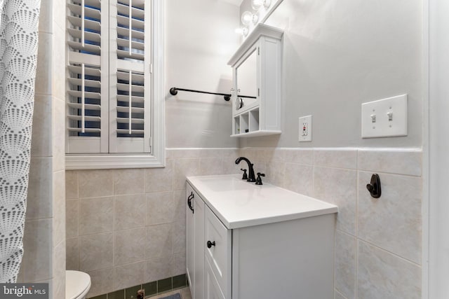 bathroom featuring toilet, tile walls, and vanity