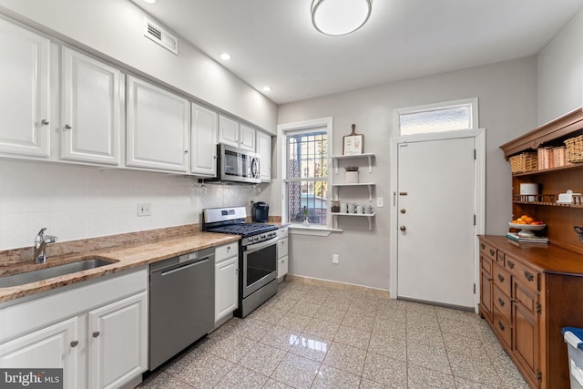 kitchen with decorative backsplash, sink, white cabinets, and stainless steel appliances