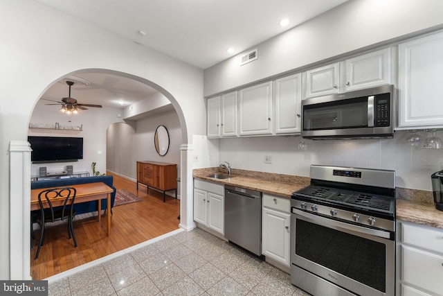 kitchen with white cabinets, appliances with stainless steel finishes, tasteful backsplash, sink, and ceiling fan