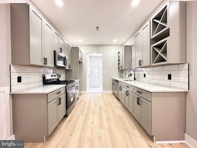 kitchen with gray cabinets, light wood-type flooring, and appliances with stainless steel finishes