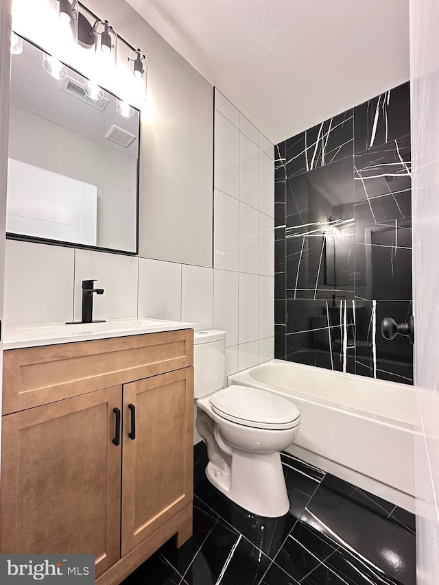 full bathroom with tiled shower / bath, vanity, toilet, and tile walls