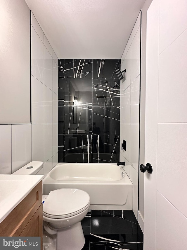 full bathroom with vanity, tile patterned flooring, tiled shower / bath combo, toilet, and tile walls