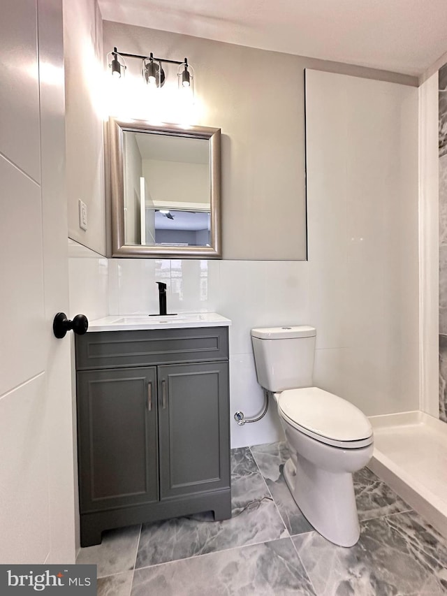 bathroom with vanity, toilet, tile walls, and walk in shower