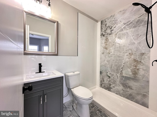 bathroom with vanity, toilet, and a tile shower