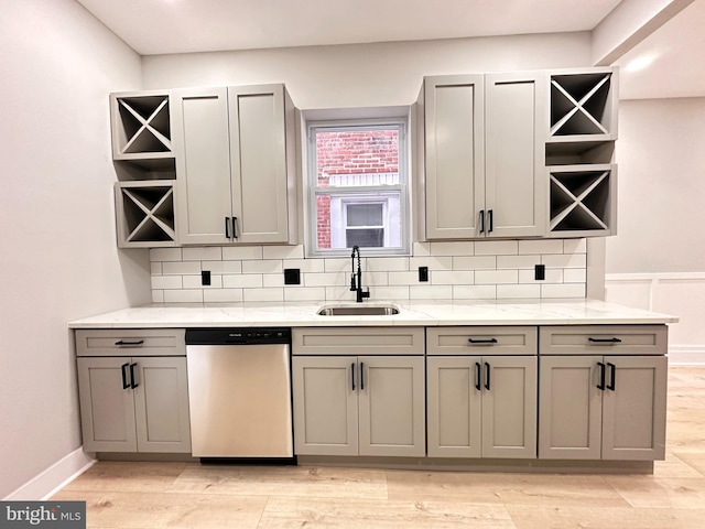 kitchen with gray cabinetry, sink, light hardwood / wood-style flooring, stainless steel dishwasher, and light stone counters