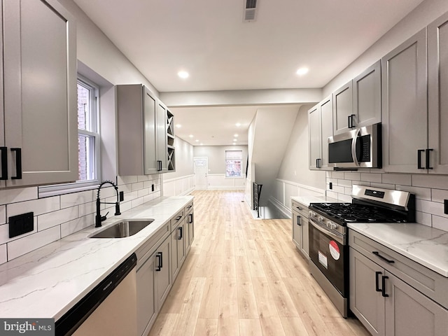 kitchen featuring light stone countertops, gray cabinetry, stainless steel appliances, sink, and light hardwood / wood-style floors