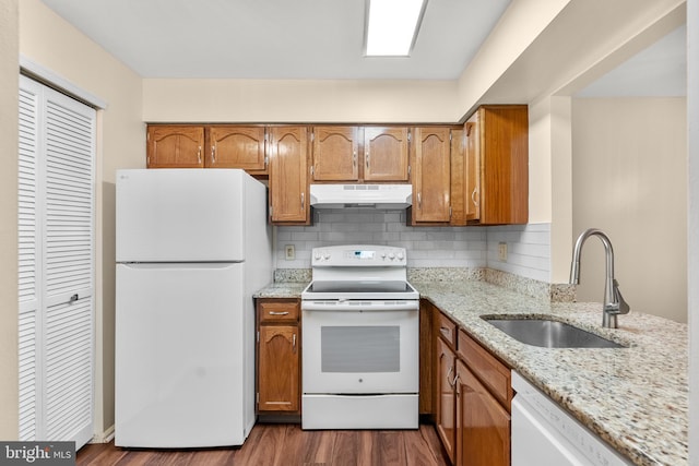 kitchen with light stone countertops, sink, dark wood-type flooring, white appliances, and decorative backsplash