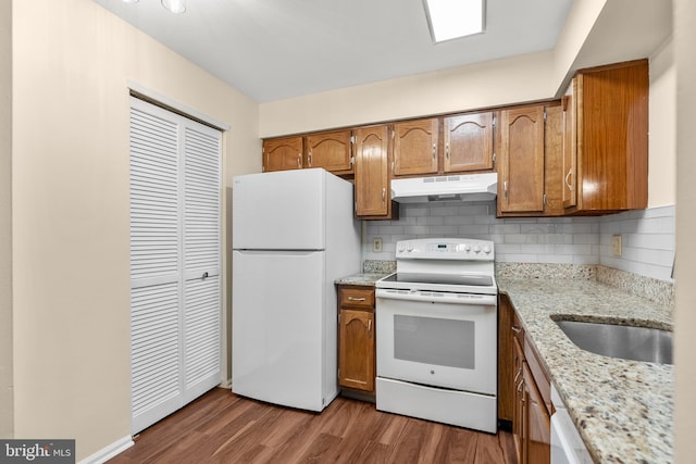 kitchen with white appliances, sink, dark hardwood / wood-style floors, light stone countertops, and tasteful backsplash