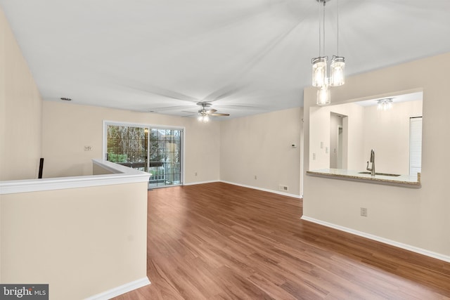 unfurnished living room with ceiling fan with notable chandelier, wood-type flooring, and sink