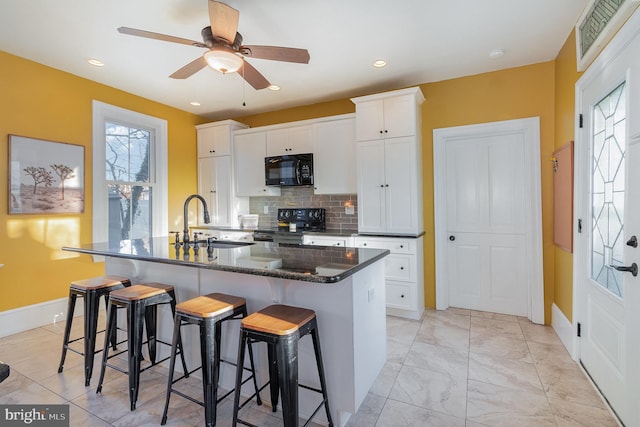 kitchen with a kitchen island with sink, white cabinets, and black appliances