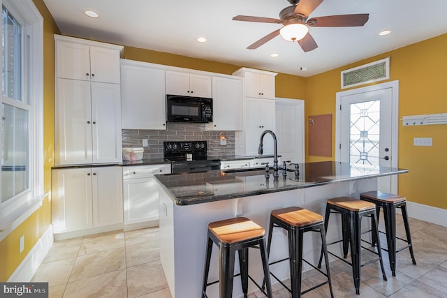 kitchen with black appliances, white cabinets, a kitchen island with sink, and sink