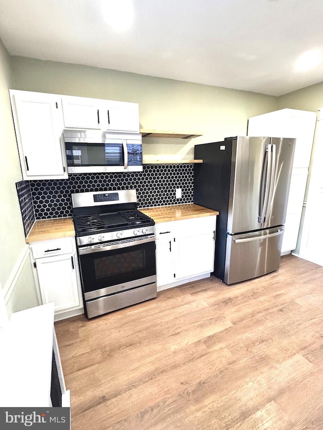 kitchen featuring wooden counters, appliances with stainless steel finishes, white cabinets, and tasteful backsplash