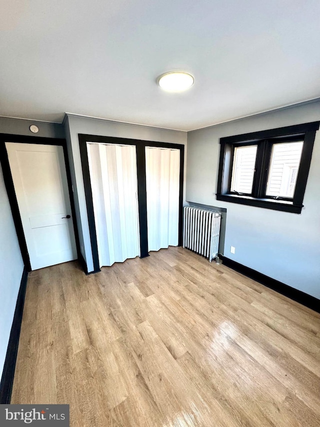 unfurnished bedroom with light hardwood / wood-style flooring and radiator