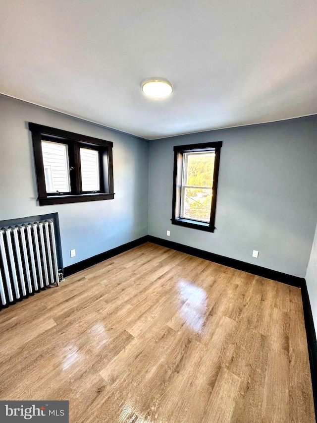 empty room with light hardwood / wood-style floors and radiator