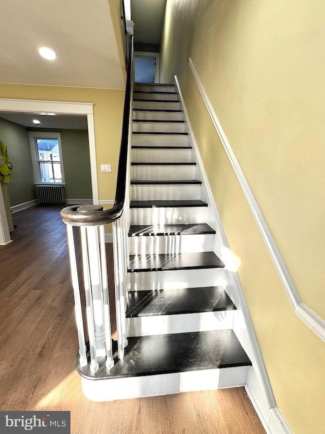 stairway with radiator, baseboards, and wood finished floors