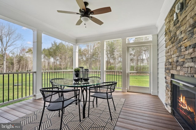 sunroom featuring ceiling fan and an outdoor stone fireplace