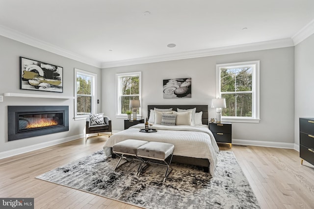 bedroom with ornamental molding, light hardwood / wood-style flooring, and multiple windows