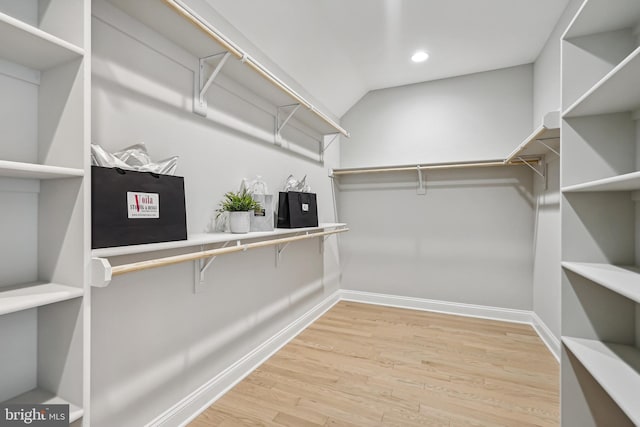 spacious closet with light hardwood / wood-style floors and lofted ceiling