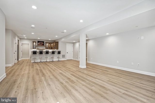 unfurnished living room with light hardwood / wood-style flooring and bar