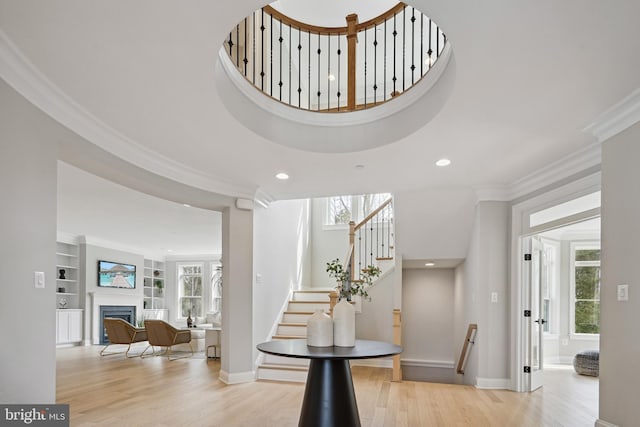 staircase with crown molding, built in features, and wood-type flooring