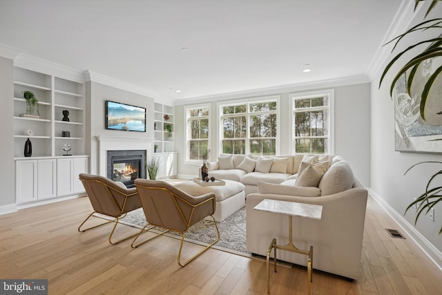 living room featuring light wood-type flooring, built in features, and ornamental molding